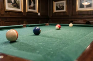 Table de billard avec tapis en feutre vert dans une salle de jeu en bois sombre, vue en plongée basse angle