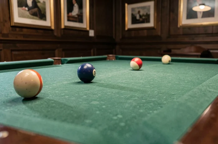 Table de billard avec tapis en feutre vert dans une salle de jeu en bois sombre, vue en plongée basse angle